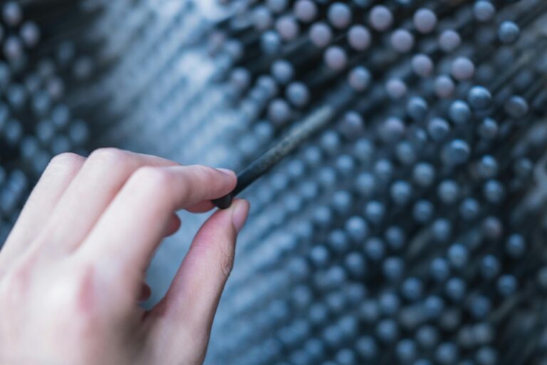 A hand interacts with a metallic art installation, showcasing texture and depth.